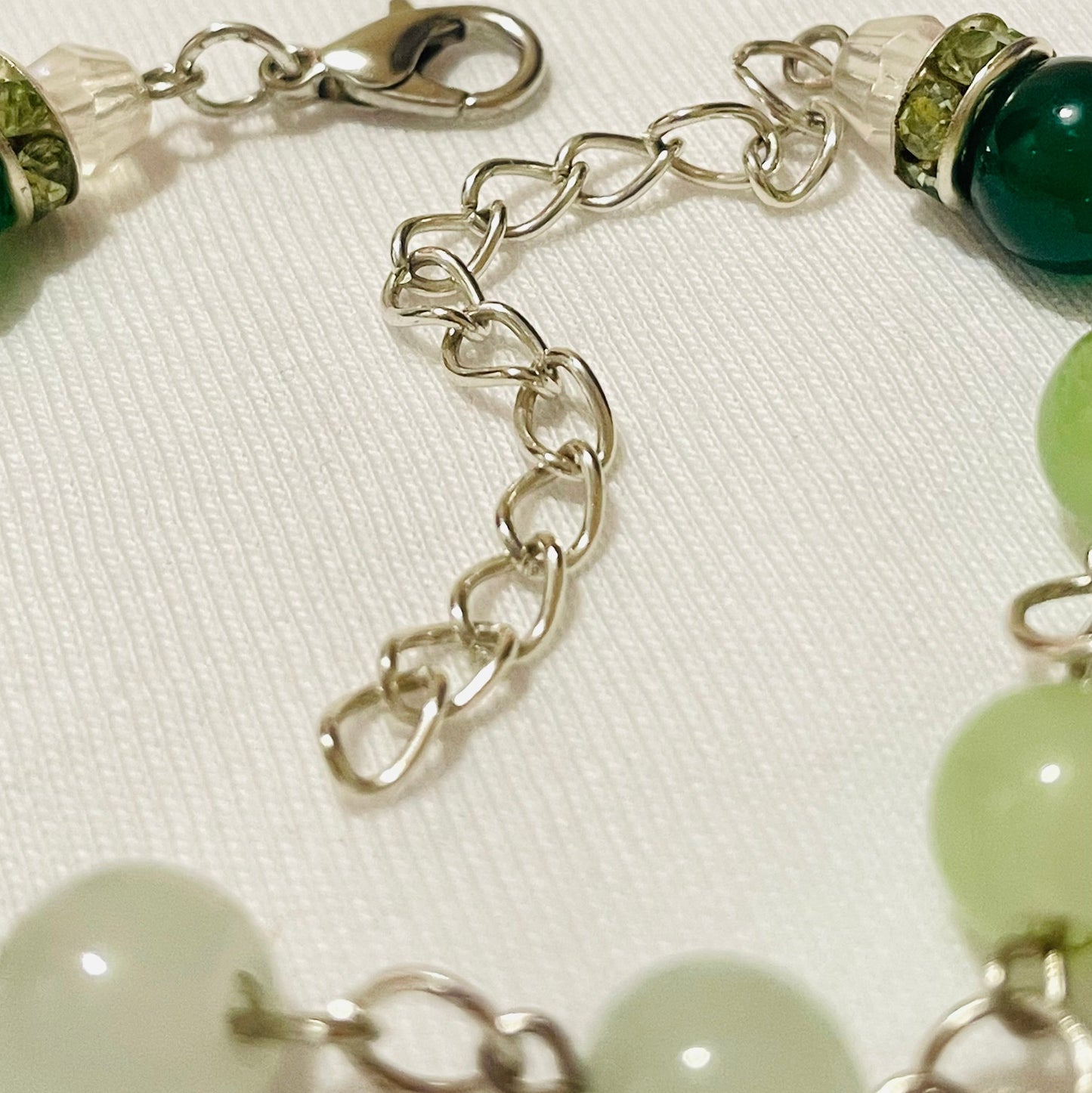 Green beaded cluster charm bracelet with star/ glass/ acrylic beads/  charms and matching green earrings with silver touches on a beige background