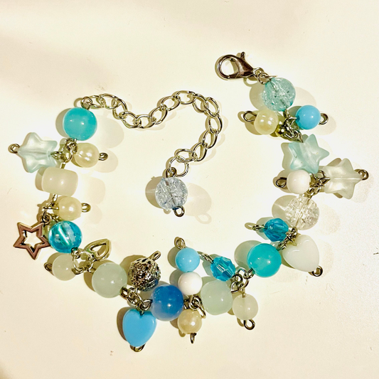 Blue beaded cluster charm bracelet with star/ glass/ acrylic beads/ charms on a beige background