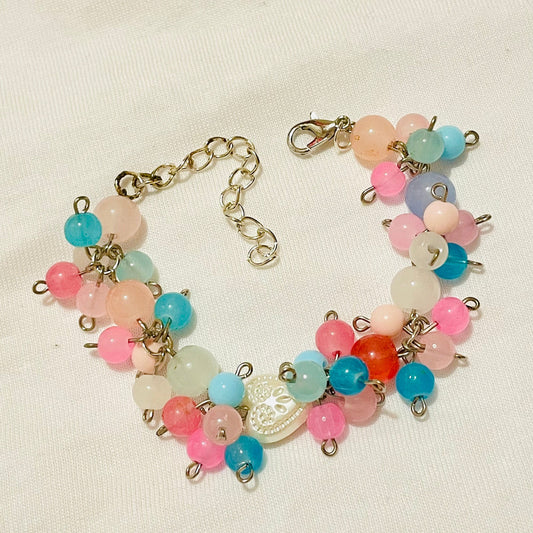 Pastel multicoloured beaded cluster charm bracelet with star/ glass/ acrylic beads/  charms on a beige background